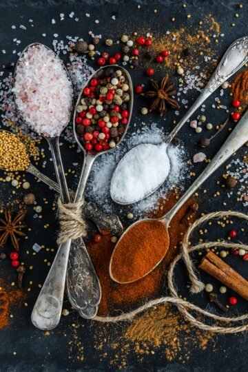 Assorted spices and seasonings arranged creatively on a dark surface, showcasing culinary art.