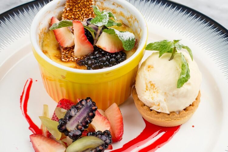 Indulge in a gourmet crème brûlée topped with blackberries and strawberries, paired with vanilla ice cream.